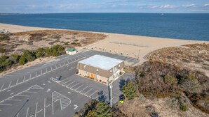 An aerial view of a building with a parking lot, adjacent to a beach and ocean. - Bayview Condo right on Lewes Beach (Lewes)