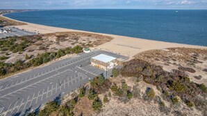 An aerial view of a coastal parking lot with a building adjacent to a beach. - Bayview Condo right on Lewes Beach (Lewes)