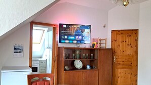 A cozy room with a wooden cabinet, a television mounted on the wall, and a dining table with chairs. - Geräumige Ferienwohnung "dresdner Stadt-terrasse" für 5 Erw., Kinder Willkommen (Dresden)