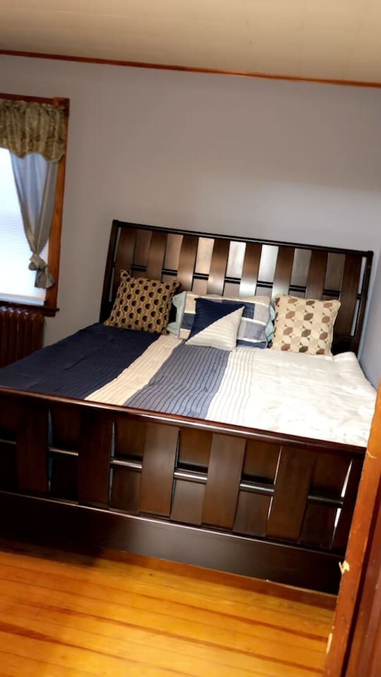 A bed with a wooden headboard, a patterned pillow, and a striped blanket.