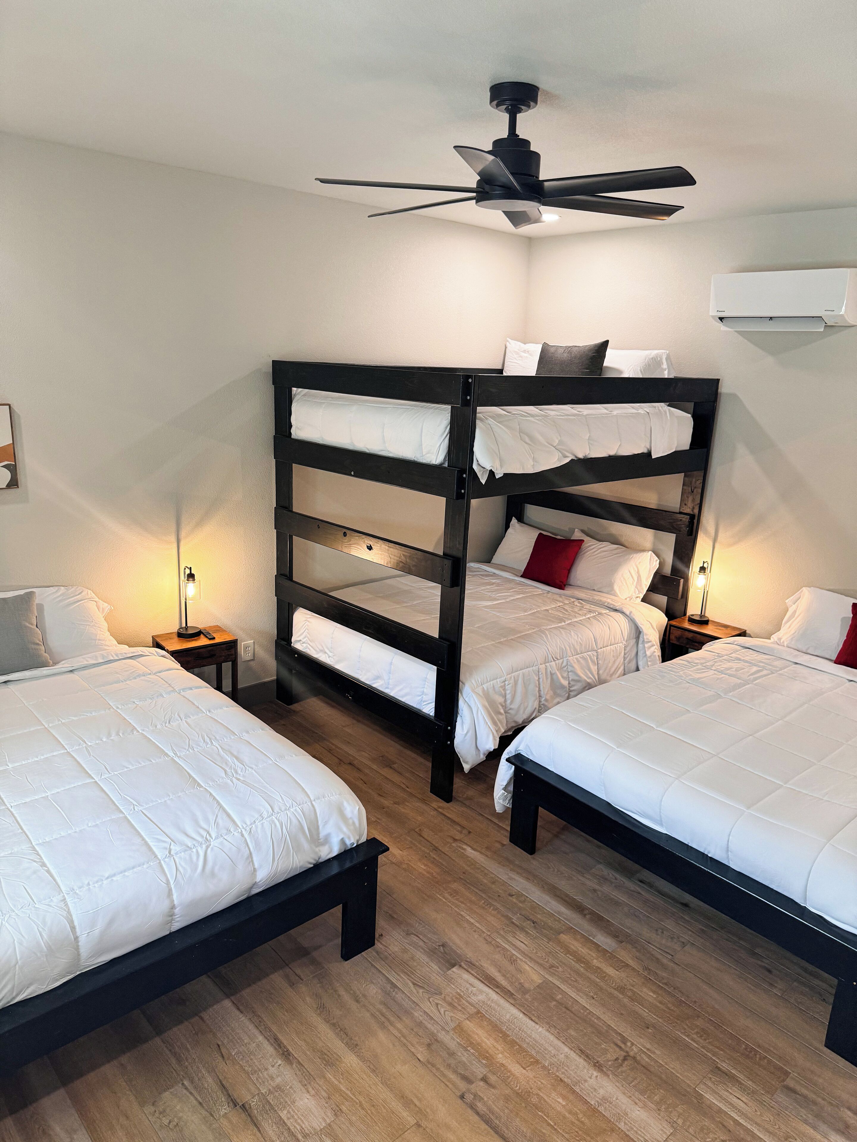 A room with bunk beds, a ceiling fan, and a wall-mounted air conditioner.