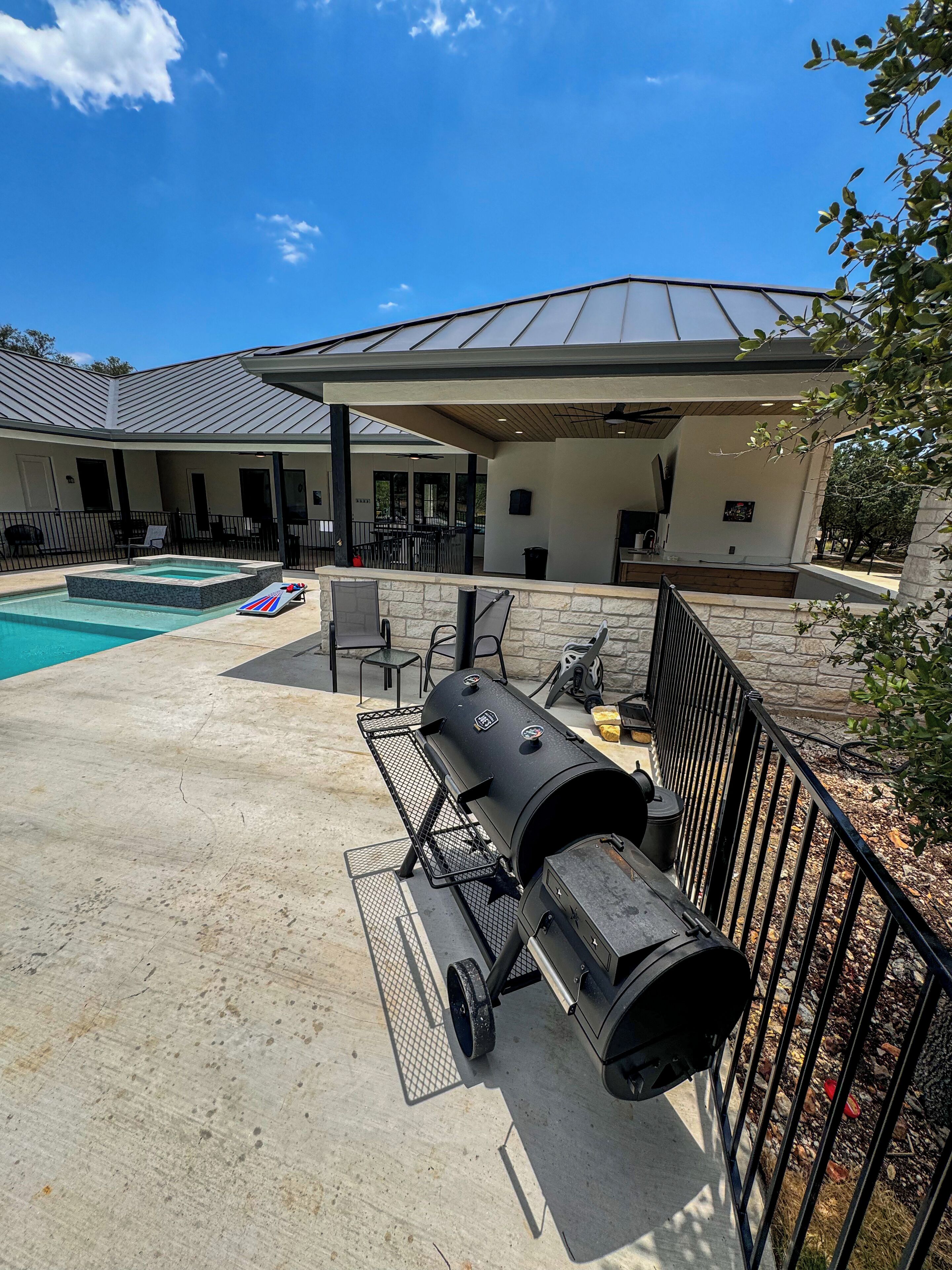 Un pati amb una barbacoa, una piscina i mobiliari d'exterior.
