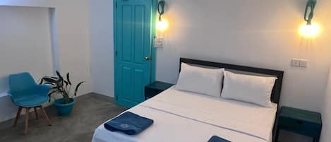 A hotel room with a bed, two bedside tables, a chair, a potted plant, and a door.