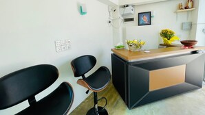 Una cocina moderna con una isla central, dos sillas negras, una mesita con un florero y un cuadro colgado en la pared.