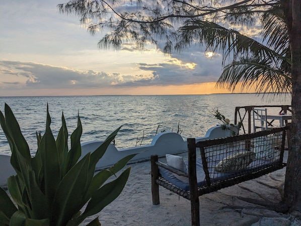 A beach view with a hammock and a white structure, likely a beach chair or table, near the water. - Lala Land Lodge (Kizimkazi)