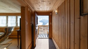 A wooden interior hallway with a view to a balcony and outside scenery. - Holiday home Nüssli for 6 people with fantastic mountain views (Wildhaus)
