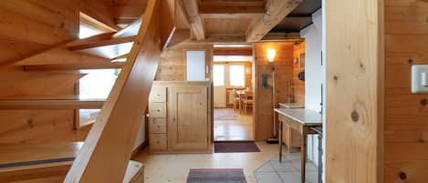 A wooden interior with a staircase, a kitchen area, and a dining space.