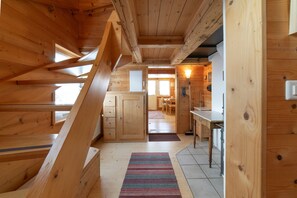 A wooden interior with a staircase, a kitchen area, and a dining space.
