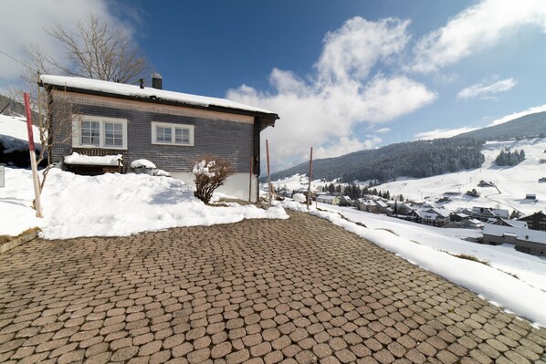 A house with a paved driveway and snow-covered surroundings.