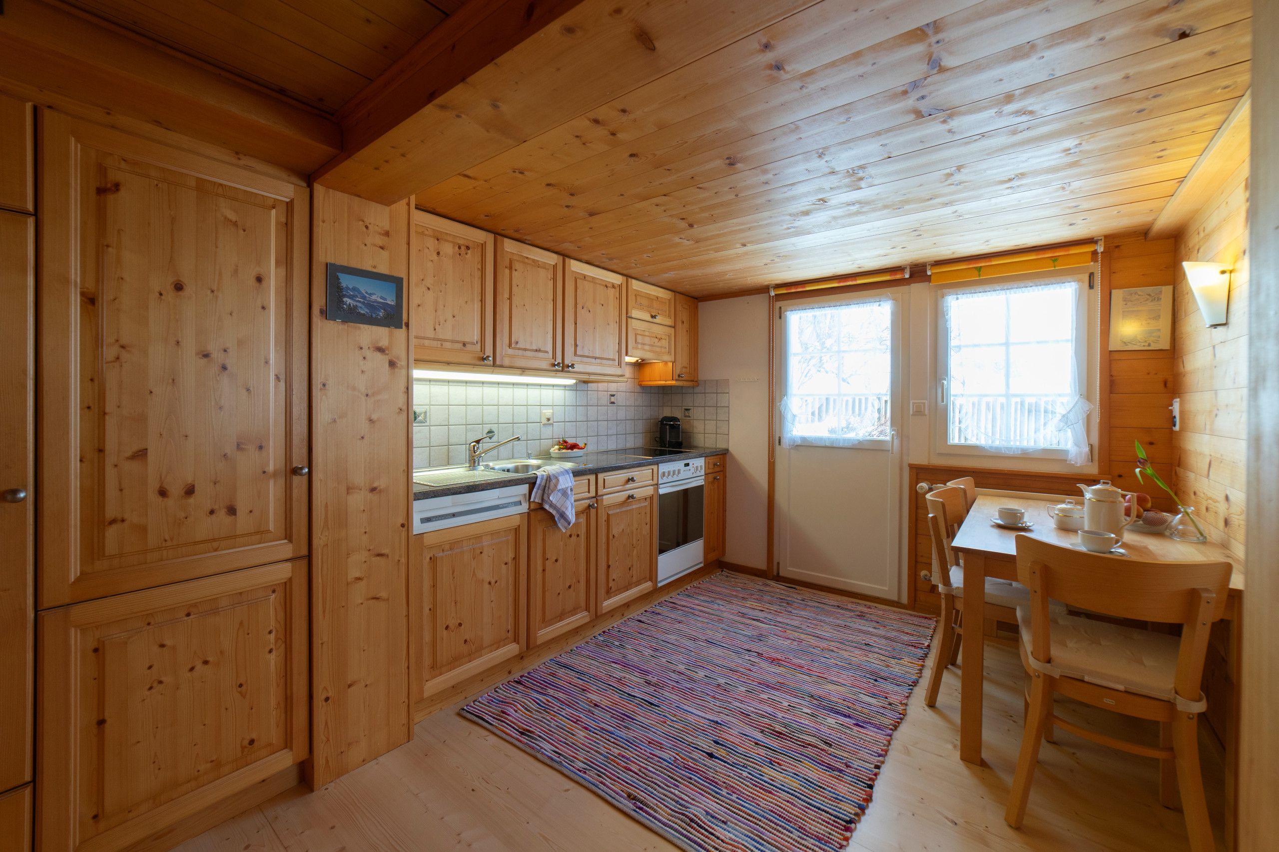 Ein Holzblockhaus-Interieur mit Küche, Essbereich und einem Fenster mit Blick.