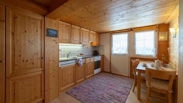 Ein Holzblockhaus-Interieur mit Küche, Essbereich und einem Fenster mit Blick.