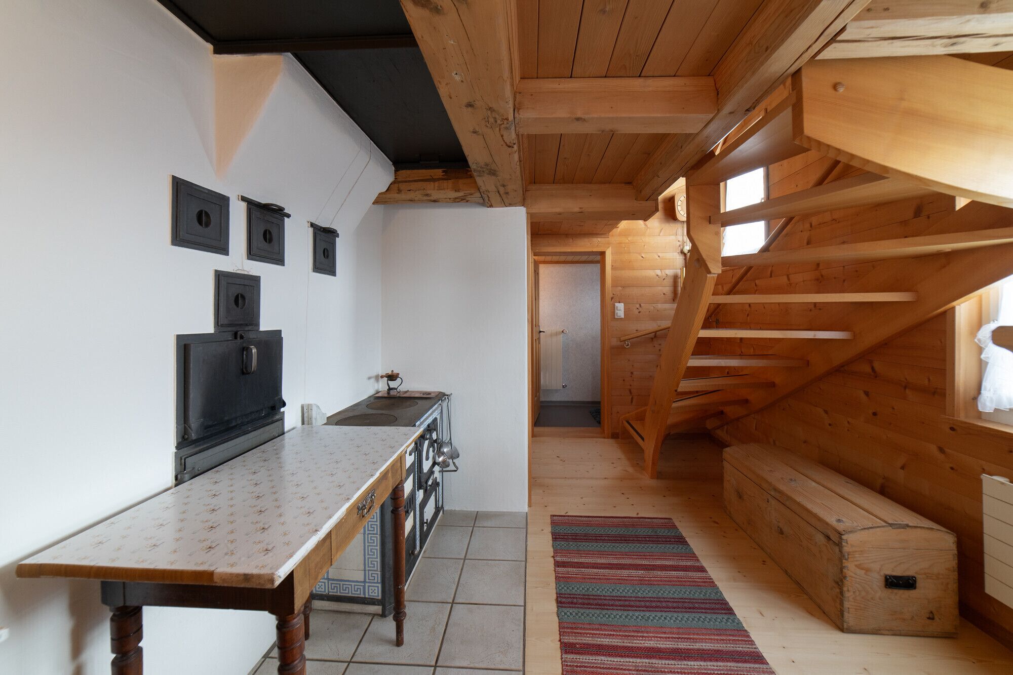 Cucina rustica con travi in legno, un fornello e pavimento piastrellato.