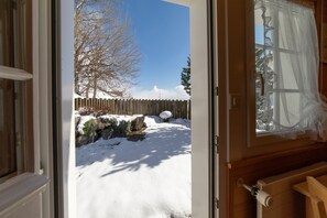 A view through an open door to a snowy outdoor area with a wooden fence and a clear blue sky. - Holiday home Nüssli for 6 people with fantastic mountain views (Wildhaus)