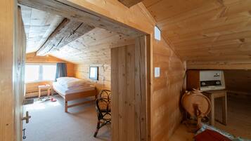 Ein Holzhütten-Zimmer mit einem Bett, einem Sessel, einem Tisch mit Radio und einem Fenster.