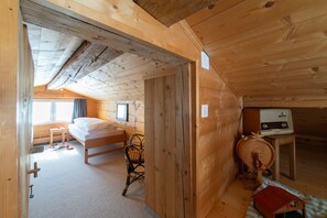 A wooden cabin room with a bed, a chair, a table with a radio, and a window. - Holiday home Nüssli for 6 people with fantastic mountain views (Wildhaus)