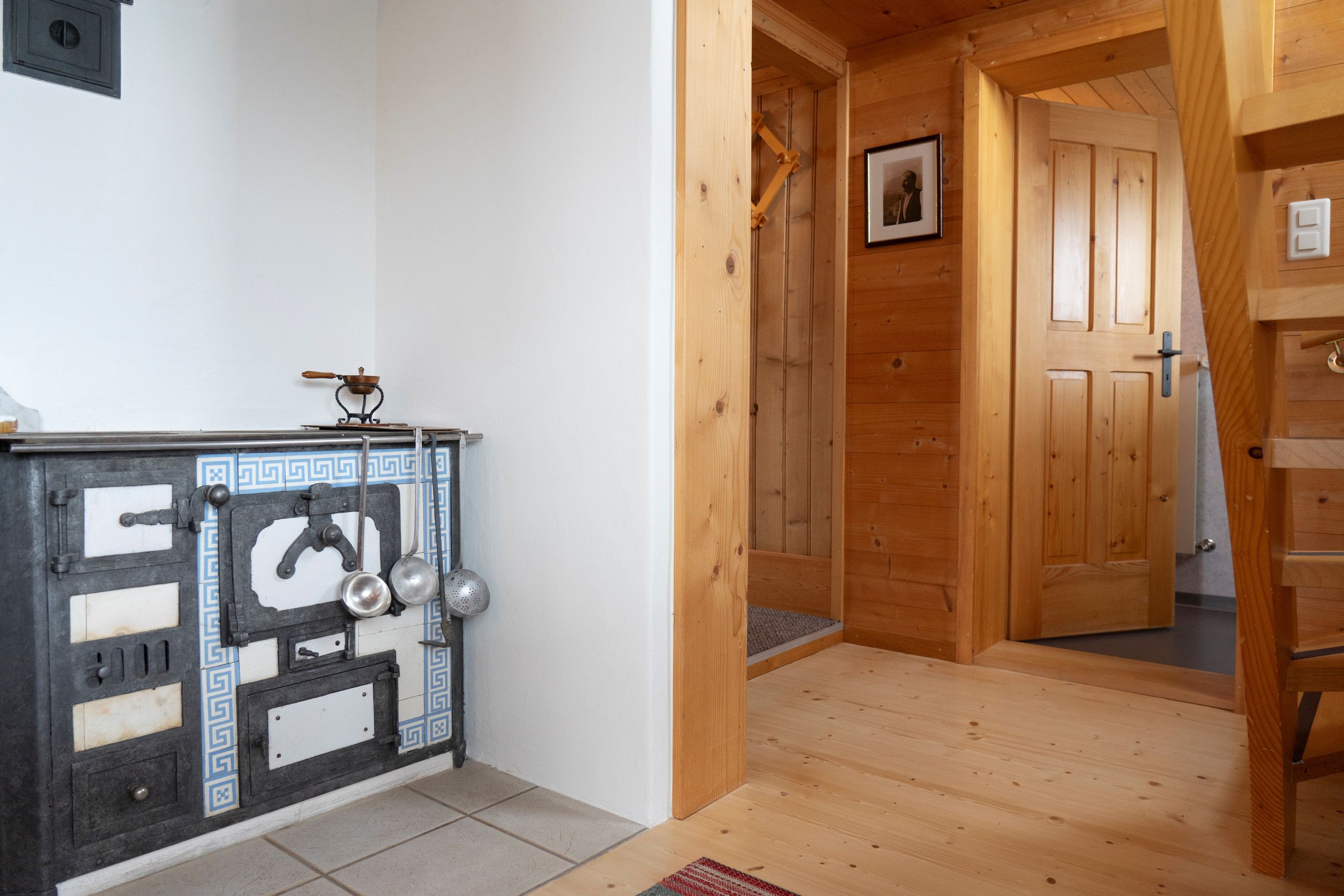 Un intérieur en bois avec un mur recouvert de carreaux, une porte et une petite étagère contenant des ustensiles de cuisine.