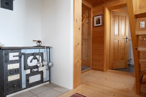 A wooden interior with a tiled wall, a door, and a small shelf with kitchen utensils. - Holiday home Nüssli for 6 people with fantastic mountain views (Wildhaus)