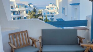 En balkon med et træbord, to træstole og en grå sofa.