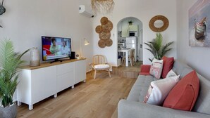 Moderni olohuone, jossa on televisio, sohva ja ruokailutila.