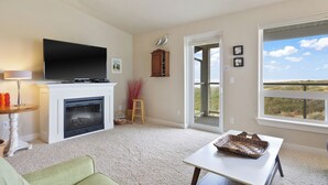 A living room with a fireplace, television, and a view through a sliding door.