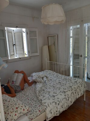 Cozy retreat with a single bed, floral-patterned bedspread, and a window with white shutters.