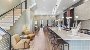 Eine moderne Küche mit einer großen Kochinsel, Barhocker und einer Treppe mit Geländer.