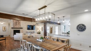 Un comedor amplio con una mesa y sillas de madera, una lámpara moderna y una chimenea.