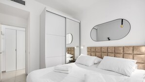 A modern hotel room with a large bed, a wardrobe, a mirror, and a headboard. - Comfortable apartment with Balcony by HolyGuest (Tel Aviv)