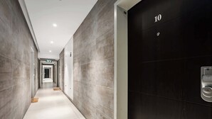 A hallway with a dark door labeled '10', a light-colored floor, and a tiled wall. - Comfortable apartment with Balcony by HolyGuest (Tel Aviv)