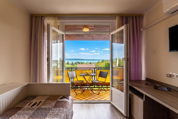 Ein Balkon mit Schachbrettfußboden, einem Tisch, zwei Stühlen und Blick auf die Landschaft.