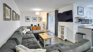 Una sala de estar moderna con un sofá seccional gris, una mesa de centro de madera y un televisor montado en la pared.