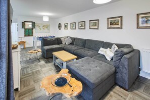 Ein modernes Wohnzimmer mit einem Ecksofa, einem Couchtisch aus Holz und einer Weltkarte an der Wand.