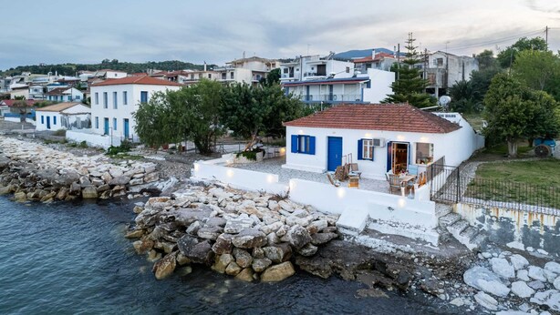 A coastal town with white buildings, a stone wall, and a clear view of the sea. - Seafront Evi's Hideaway - Petalidi Cozy Nest (Petalidi)