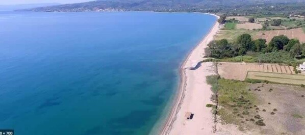 An aerial view of a coastal area with a beach and adjacent fields. - Seafront Evi's Hideaway - Petalidi Cozy Nest (Petalidi)