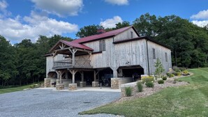 A large wooden barn with a red roof, a covered porch, and a garage. - RV lot Hook Up, 5 minutes off I 80. Peacefully hidden behind our vintage barn.  (Loganton)