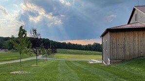 A grassy field with a wooden barn and a few trees. - RV lot Hook Up, 5 minutes off I 80. Peacefully hidden behind our vintage barn.  (Loganton)