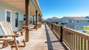 Une terrasse en bois avec des sièges extérieurs, un espace abrité et une vue sur les maisons voisines.