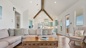 Un salon moderne avec un canapé d’angle, une table basse en bois et un fauteuil.