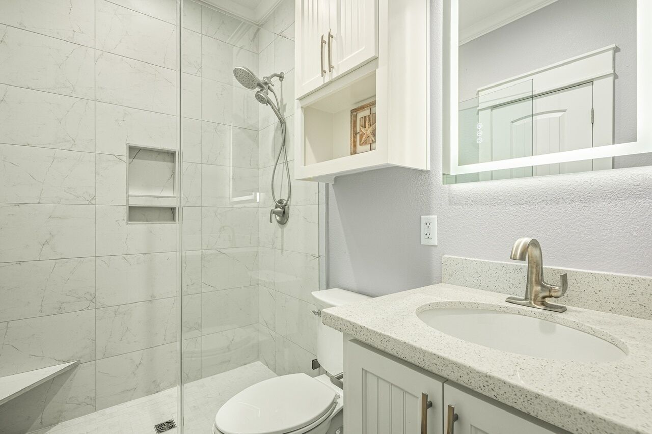 Ein modernes Badezimmer mit einer Duschkabine aus Glas, einer weißen Toilette und einem freistehenden Waschbecken mit einem Wasserhahn.