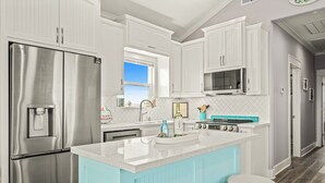 Een moderne keuken met witte kasten, roestvrijstalen apparatuur en een blauw eiland.