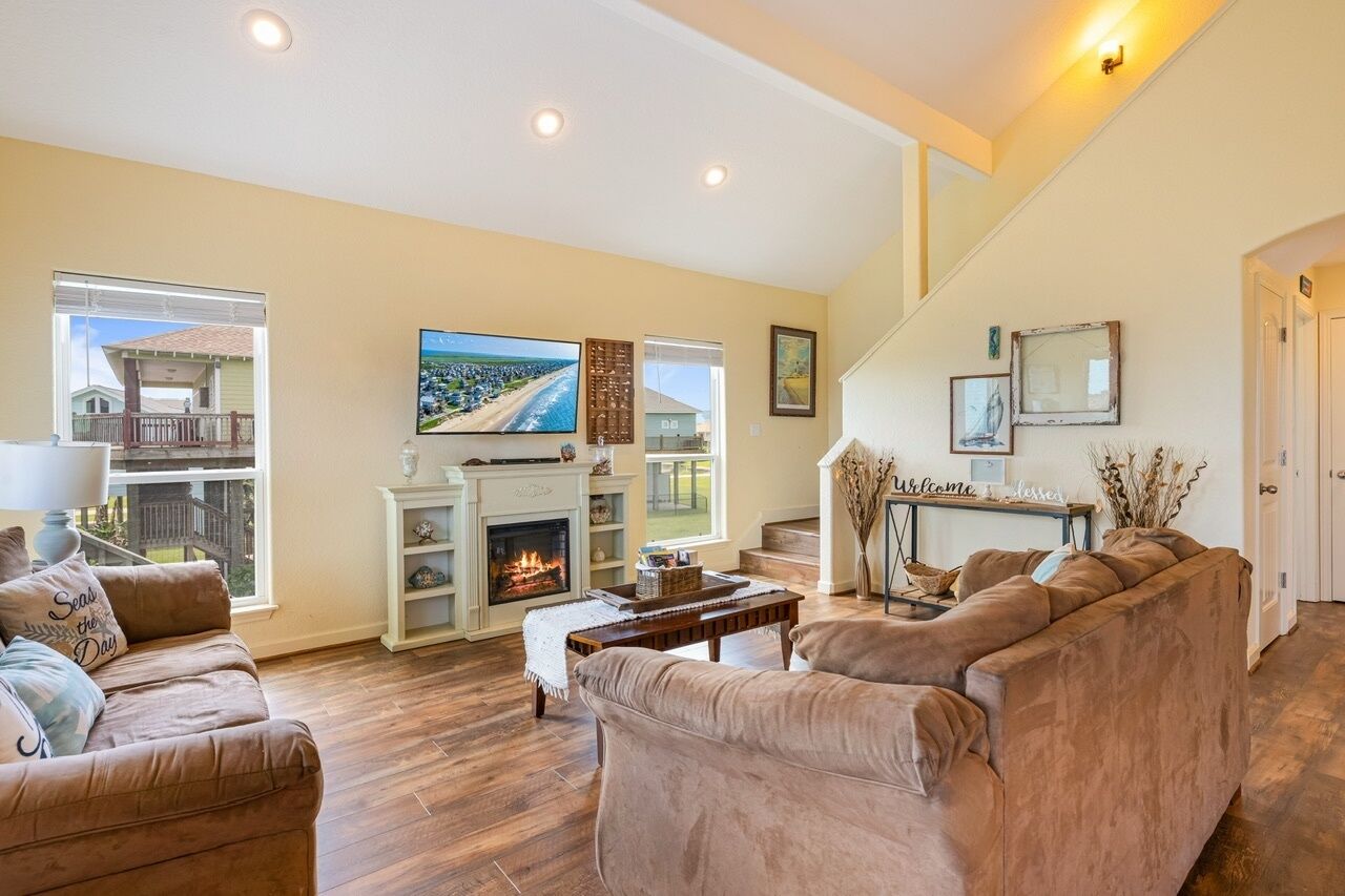 A living room with a fireplace, a television, and a staircase leading to an upper level.