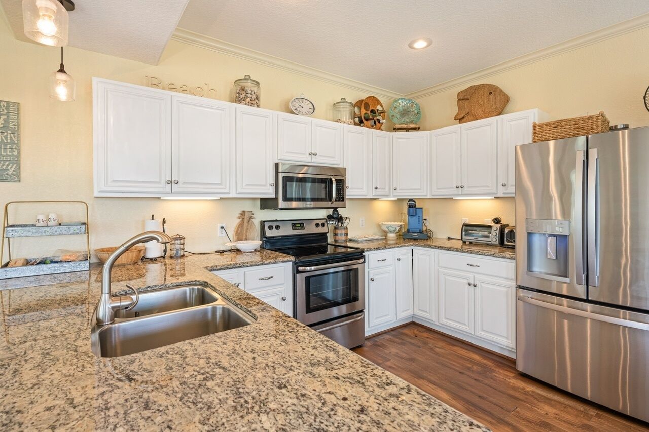 A kitchen with white cabinets, stainless steel appliances, granite countertops, and a built-in oven.