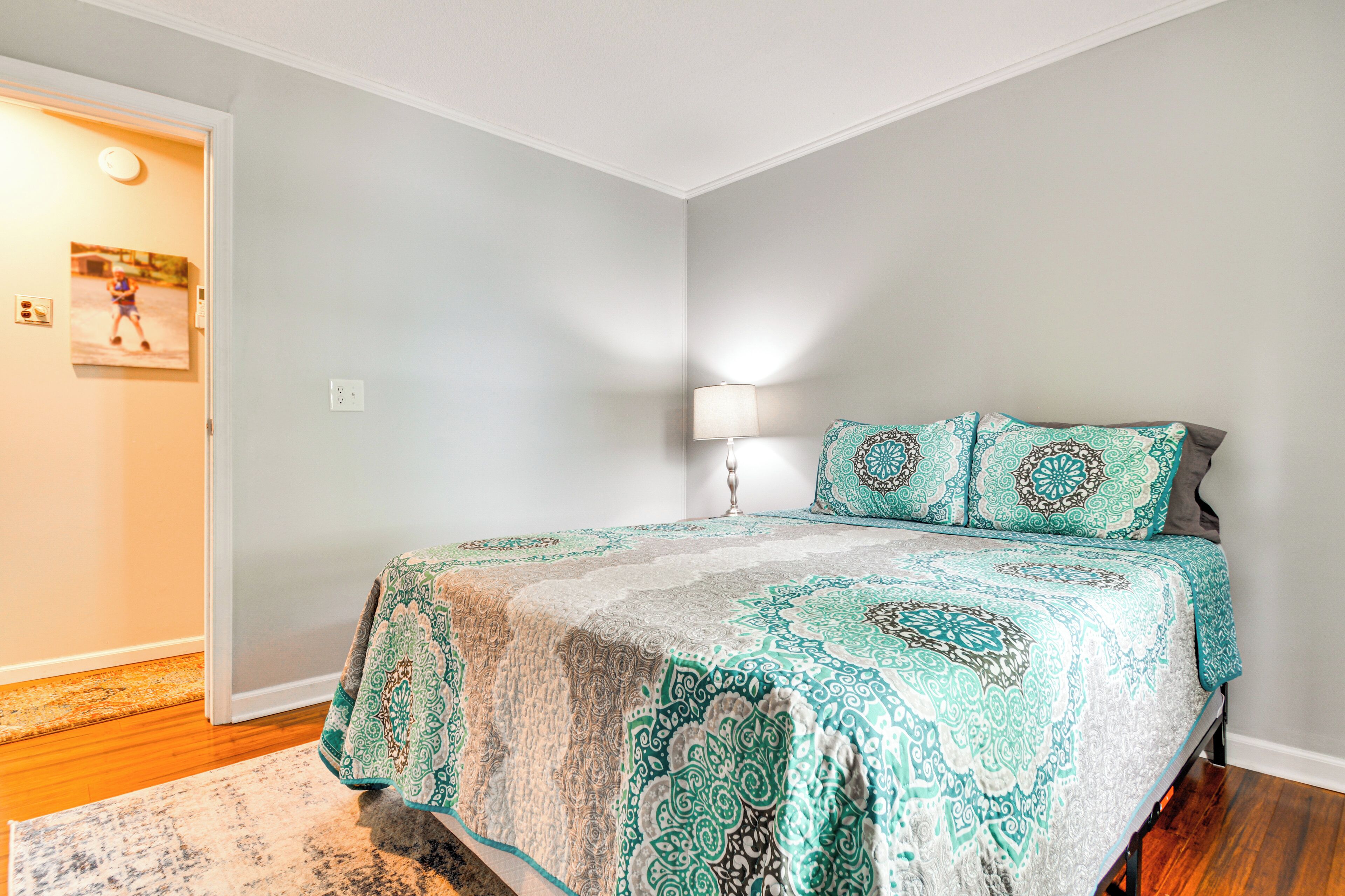 A bedroom with a bed, a nightstand, a lamp, and a door.