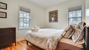 Ein Schlafzimmer mit einem Bett, einem Schminktisch und zwei Fenstern.