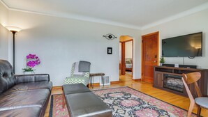 Ein Wohnzimmer mit einer Ledersofa, einer Bank, einem gemusterten Teppich, einem Fernseher und einer Holzkabine.