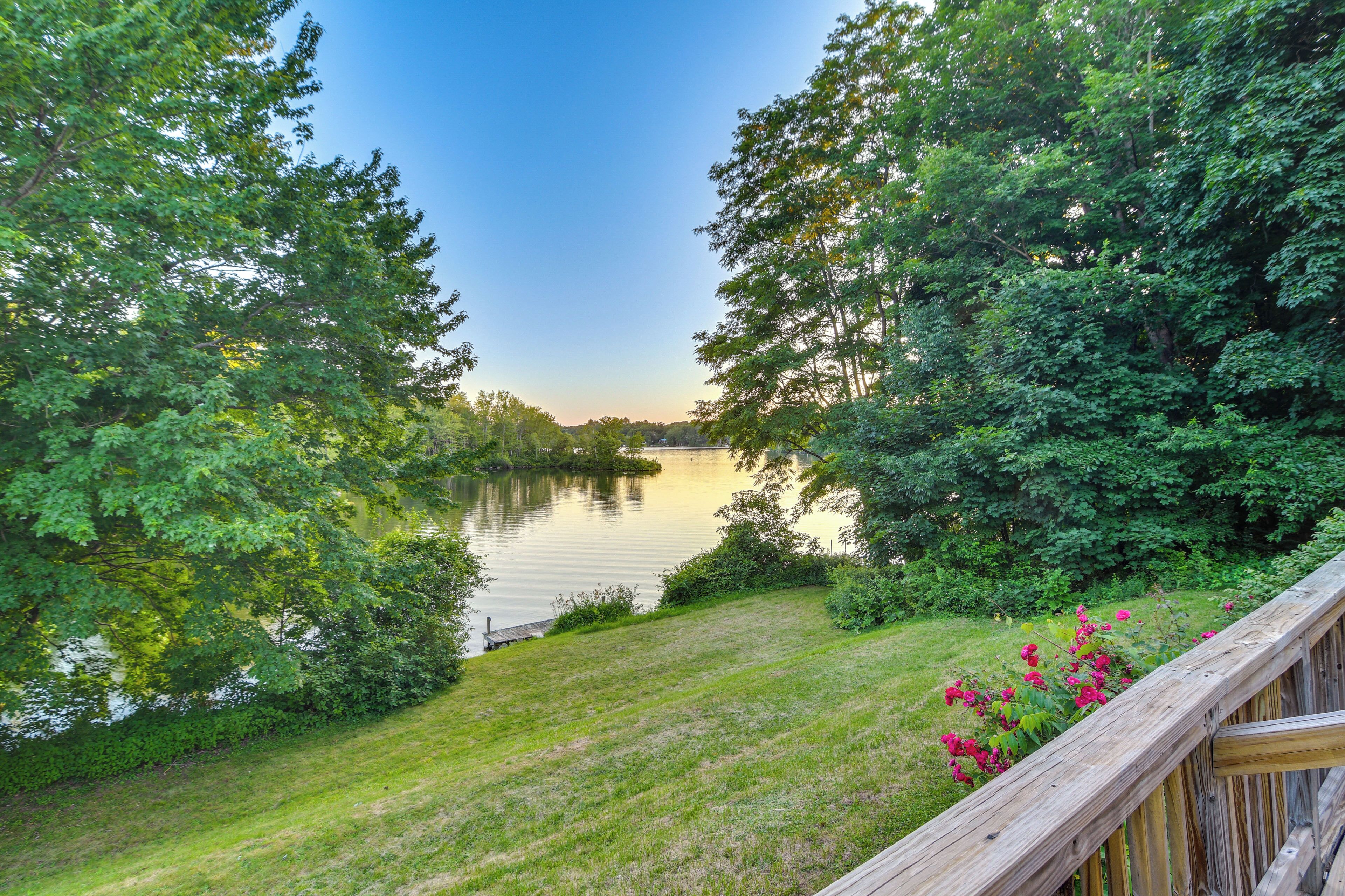 A lakeside view with a wooden deck and lush greenery.