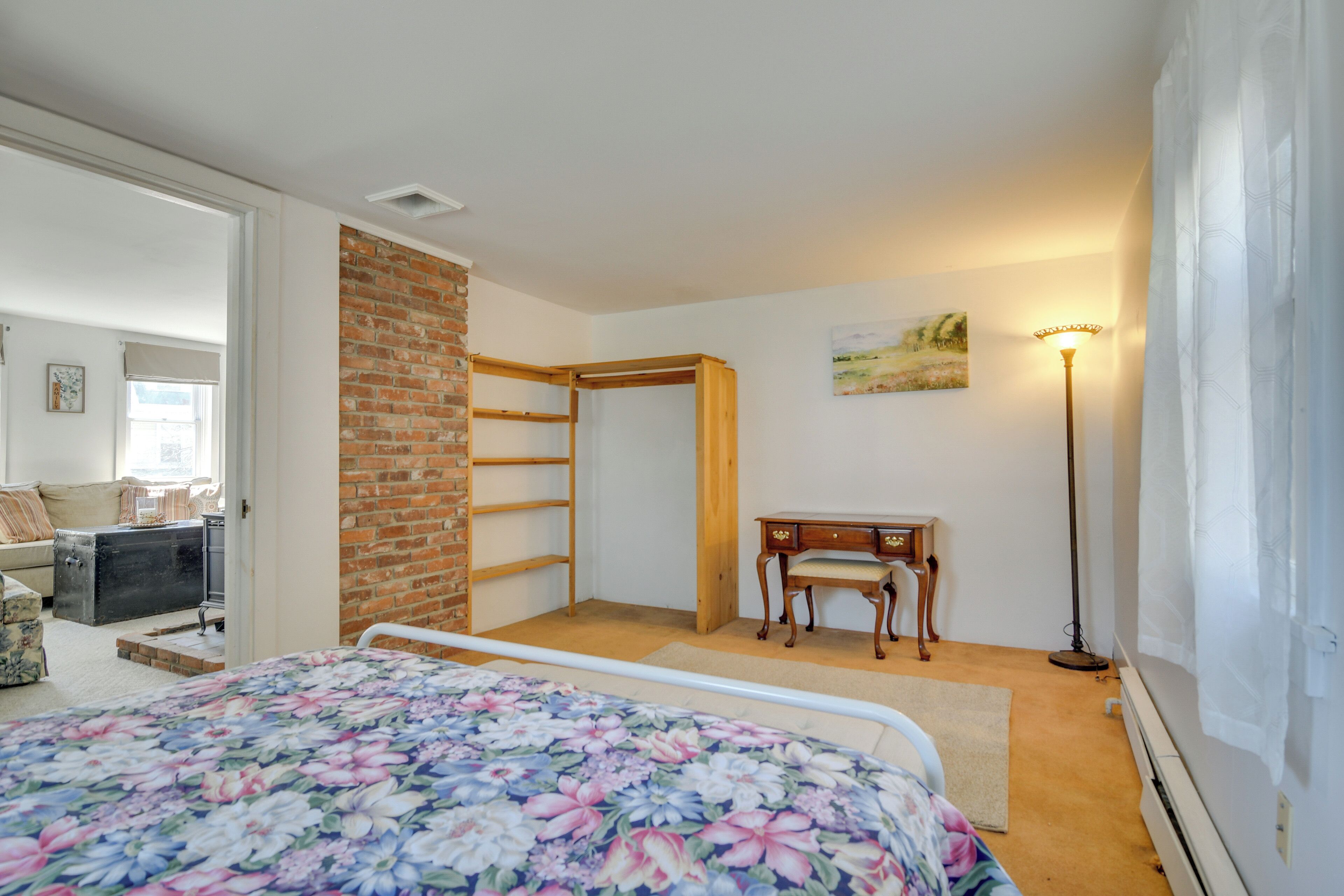 Ein Schlafzimmer mit einem Bett, einem Schreibtisch, einem Stuhl, einer Lampe und einer Ziegelwand.