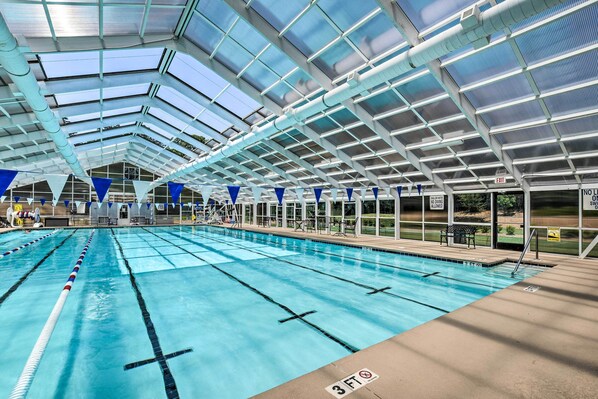 An indoor swimming pool with clear lanes, a covered roof, and a lifeguard station.