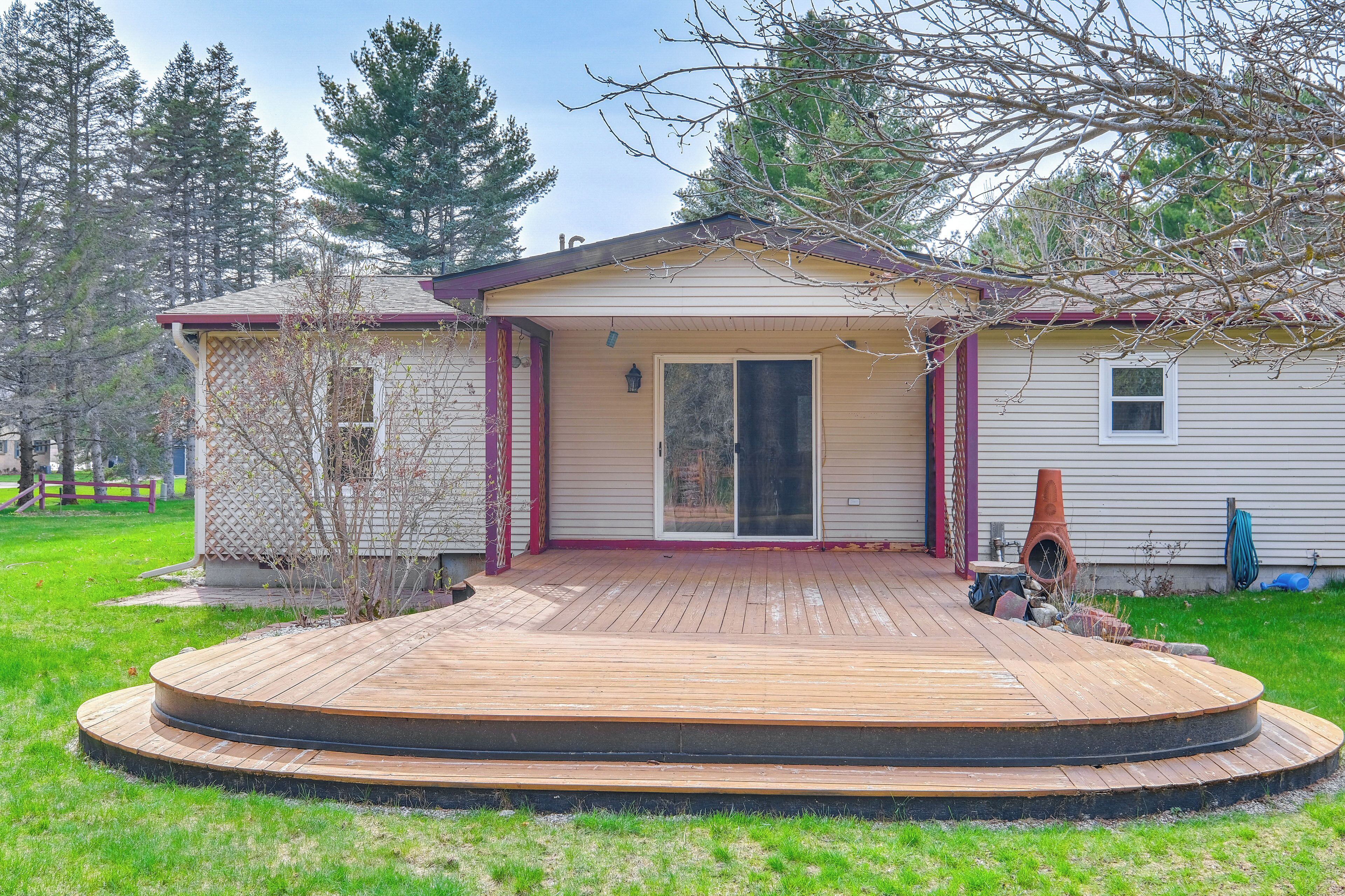 A single-story house with a wooden deck, a sliding glass door, and a small attached garage.