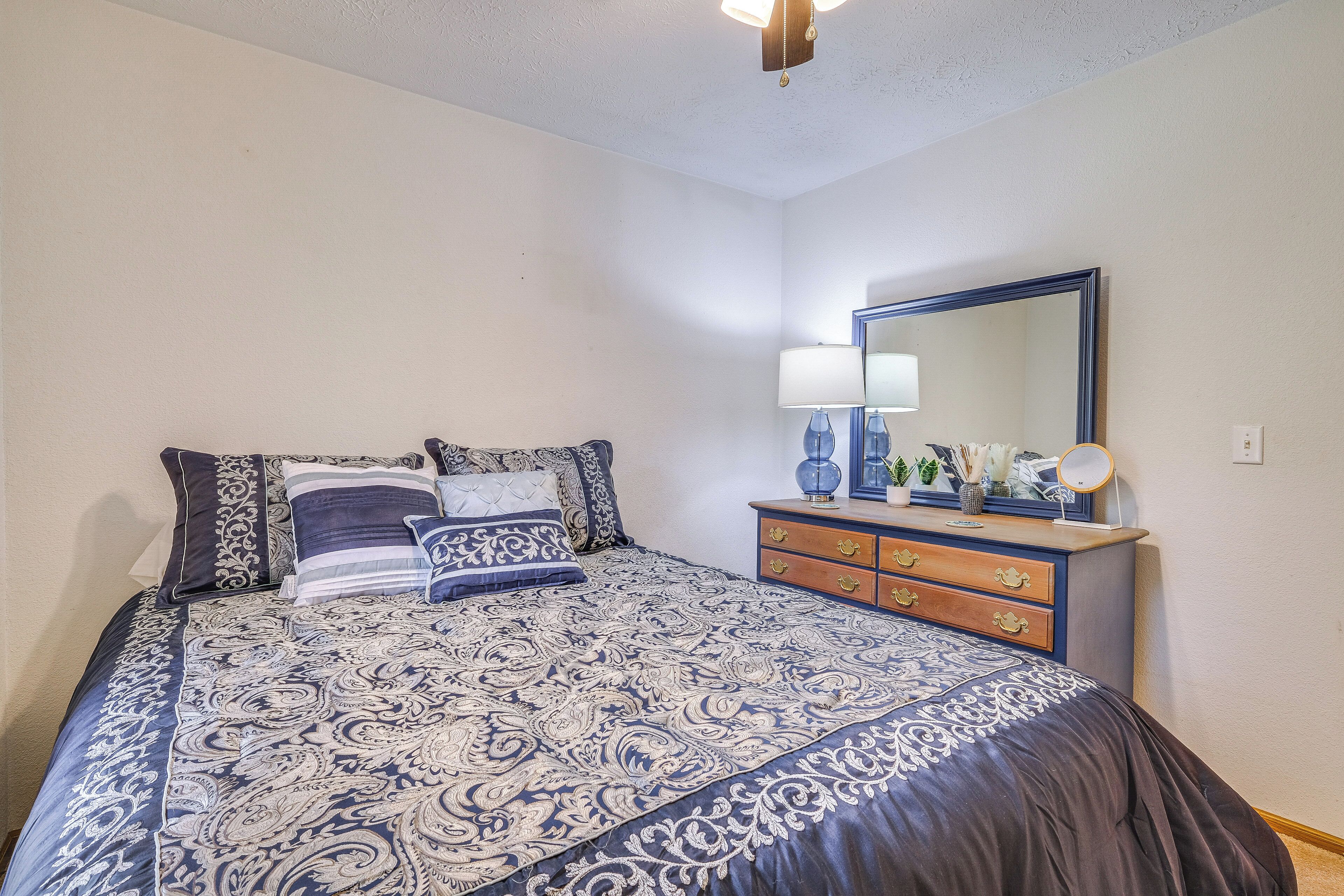 Een slaapkamer met een groot bed, een kast met lades, een spiegel en een lamp.